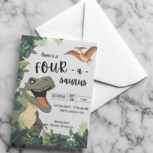 May include: A white invitation card with a dinosaur theme, featuring a green dinosaur illustration and the text "Owen is a Four-a-saurus." Includes date, time, and RSVP information. Accompanied by a white envelope.