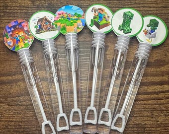 Op de afbeelding: Een set van zeven doorzichtige plastic bellenblaasstokken met witte handvatten en bellenblazers. Elke stok wordt gecombineerd met een ronde sticker met Minecraft-thema graphics. De stickers hebben groene randen en tonen verschillende personages en scènes.