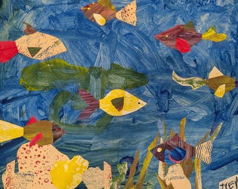May include: A mixed-media collage artwork featuring multiple paper-cutout fish in various colors and patterns swimming against a blue painted background. The composition includes green aquatic plants, textured coral-like shapes, and the text "THEA".