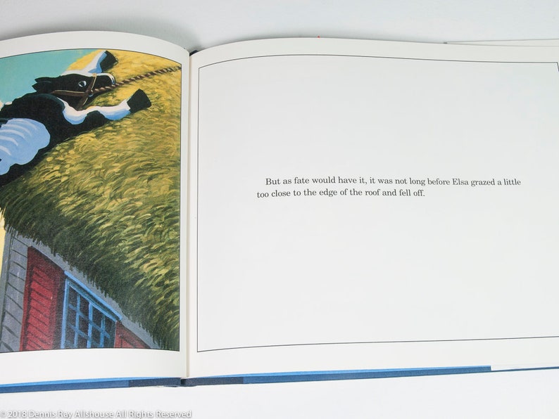 May include: An open book illustration featuring a black and white cow on a thatched roof. The cow is wearing a harness. The text reads: "But as fate would have it, it was not long before Elsa grazed a little too close to the edge of the roof and fell off."