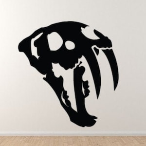 May include: Black silhouette of a saber-toothed cat skull with large fangs. The skull is facing left and has a detailed design.