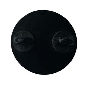May include: Black metal pin back with two metal clasps on the back.