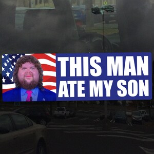 May include: A rectangular bumper sticker with the text "THIS MAN ATE MY SON" in white letters on a blue background. The left side features a portrait of a man with a beard and the American flag.