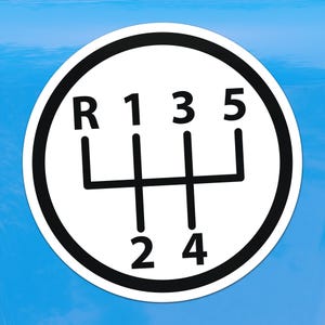 Può includere: Adesivo circolare bianco con un motivo di cambio nero con le lettere "R", "1", "2", "3", "4" e "5". L'adesivo ha un bordo nero ed è posto su uno sfondo blu.