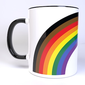 May include: White ceramic mug with a black handle and a rainbow flag design. The rainbow has eight colors: black, brown, red, orange, yellow, green, blue, and purple.