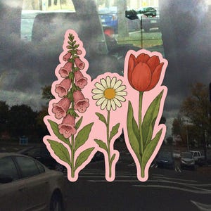 May include: A pink sticker with three flowers: a pink foxglove, a white daisy, and a red tulip. The flowers are drawn in a vintage style.
