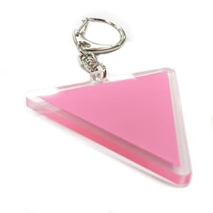 Puede incluir: Un llavero de color rosa en forma de triángulo con un anillo y una cadena de metal plateado.