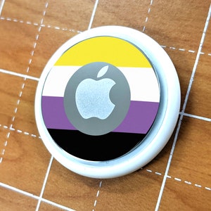 May include: A white phone case with a black, purple, white, and yellow pride flag design. The Apple logo is in the center of the flag.