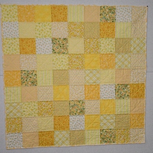 May include: A square patchwork quilt featuring a grid of various yellow and white fabric squares. The design includes a mix of solid yellow, gingham, floral, and plaid patterns, all stitched together with visible diagonal quilting lines.
