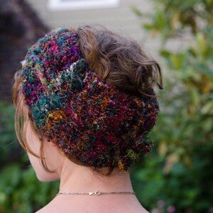 May include: A colorful, hand-knitted headband with a textured, multi-colored design. The headband features a mix of vibrant colors, including red, green, and yellow. This accessory is a stylish addition to any outfit.