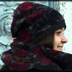 Könnte beinhalten: Ein schwarzes Mützen- und Schal-Set mit einem roten und grauen Muster. Die Mütze ist im Beanie-Stil gehalten, und der Schal ist um den Hals gewickelt. Das Set ist aus einem weichen, strukturierten Material.