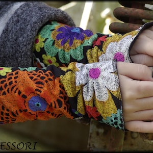 Könnte beinhalten: Bunte, florale bestickte Armwärmer mit schwarzem Hintergrund. Die Armwärmer sind aus einem weichen, dehnbaren Stoff gefertigt und zeigen verschiedene florale Designs in Orange-, Gelb-, Grün-, Blau- und Rosatönen.