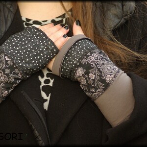 Könnte beinhalten: Ein Paar schwarze und weiße fingerlose Handschuhe mit einem Blumenmuster. Die Handschuhe sind aus einem weichen, dehnbaren Stoff gefertigt und haben eine bequeme Passform.