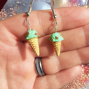 Könnte beinhalten: Ein Paar silberne Ohrringe mit einem Anhänger in Form einer grünen und braunen Eistüte. Die Eistüte ist aus Polymer Clay gefertigt und hat ein realistisches Aussehen.