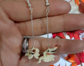 May include: A pair of silver dangle earrings with white clay charms shaped like the character Jack Skellington from the movie The Nightmare Before Christmas.
