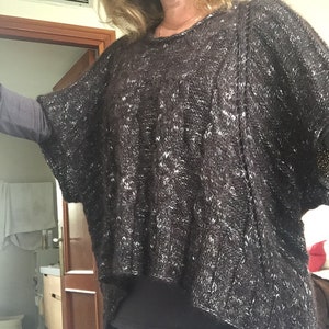 以下が含まれることがあります： 白の斑点が入った濃い茶色のニットポンチョ。 ポンチョは、丸いネックラインと短い袖を備えた、幅広でオープンなデザインです。 ニット生地は厚手で質感があり、涼しい季節に適しています。