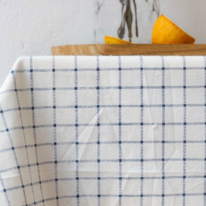 May include: A white tablecloth with a blue and white checkered pattern. The tablecloth is draped over a wooden table.