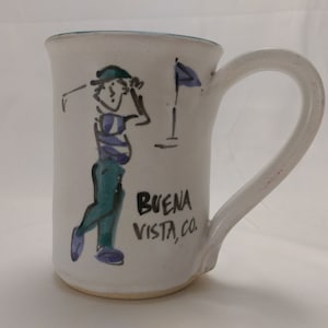 May include: White ceramic mug with a green, blue, and black illustration of a golfer and the text "BUENA VISTA, CO."