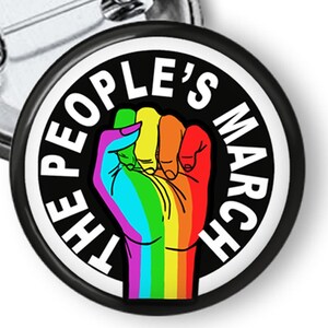 May include: A black and white button with a raised fist in the center. The fist is rainbow colored and the text "The People's March" is around the fist.