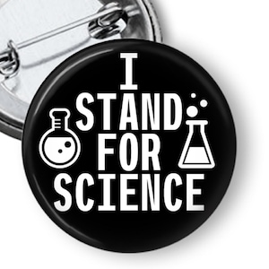 May include: Black button with white text that reads "I stand for science" with a beaker graphic on either side of the text.