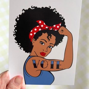 Peut inclure: Une femme avec une coiffure afro et un bandeau rouge &agrave; pois blancs fl&eacute;chit son biceps. Le mot "VOTE" est tatou&eacute; sur son bras.