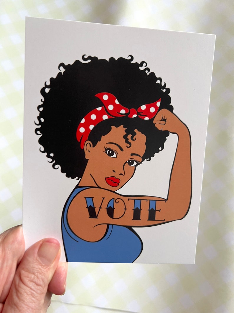 Peut inclure: Une femme avec une coiffure afro et un bandeau rouge &agrave; pois blancs fl&eacute;chit son biceps. Le mot "VOTE" est tatou&eacute; sur son bras.