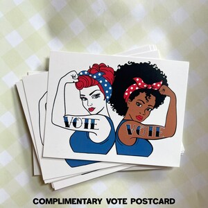 Peut inclure: Deux femmes avec des tons de peau diff&eacute;rents sont repr&eacute;sent&eacute;es dans une illustration de style vintage. Elles fl&eacute;chissent toutes les deux leurs biceps avec le mot &laquo;&nbsp;VOTE&nbsp;&raquo; tatou&eacute; sur leurs bras. Les femmes portent des d&eacute;bardeurs bleus et des bandeaux &agrave; pois rouges et blancs. L'arri&egrave;re-plan est blanc.