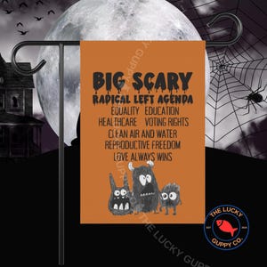 May include: A rectangular orange garden flag featuring the black text BIG SCARY RADICAL LEFT AGENDA followed by a list of terms including EQUALITY, EDUCATION, HEALTHCARE, VOTING RIGHTS, CLEAN AIR AND WATER, REPRODUCTIVE FREEDOM, and LOVE ALWAYS WINS.