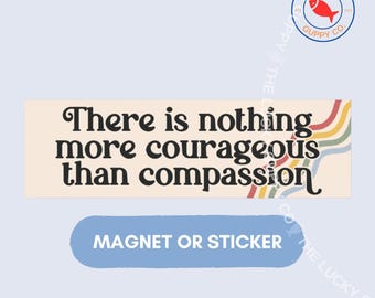 Può includere: Un adesivo o magnete rettangolare con sfondo color crema che riporta il testo nero There is nothing more courageous than compassion. Il lato destro mostra una serie di sottili linee ondulate multicolori in rosso, arancione, giallo e verde.