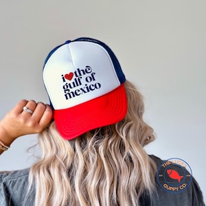 May include: A white, red, and blue trucker hat with a red heart and the text "I love the gulf of mexico" in blue lettering.