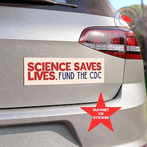 May include: A white car with a red, white, and blue bumper sticker that reads "SCIENCE SAVES LIVES. FUND THE CDC". A red star sticker with the text "MAGNET OR STICKER" is on the back of the car.
