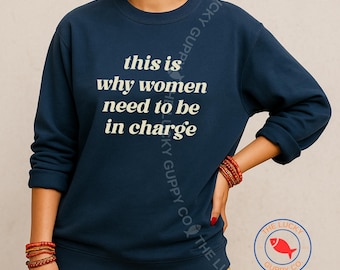 May include: Navy blue sweatshirt with the text "this is why women need to be in charge" in white. The sweatshirt has a crew neck and long sleeves. The Lucky Guppy Co. logo is visible in the bottom right corner.