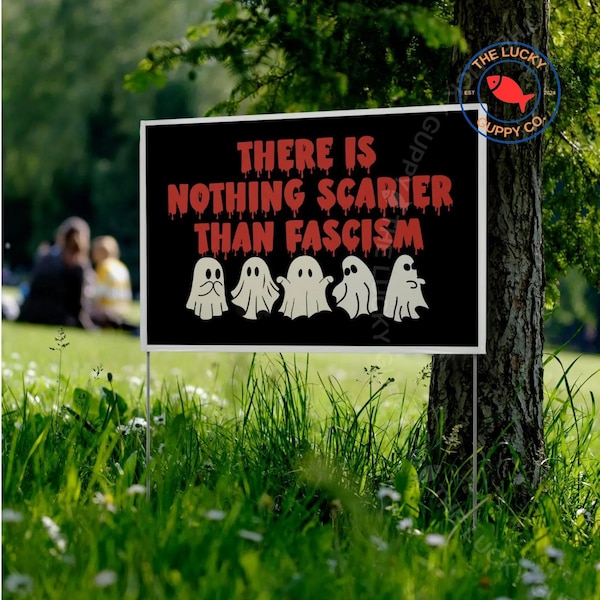May include: A black yard sign with white border, displaying the text "THERE IS NOTHING SCARIER THAN FASCISM" in red dripping font, with five white ghost illustrations. The sign is placed in a grassy area.