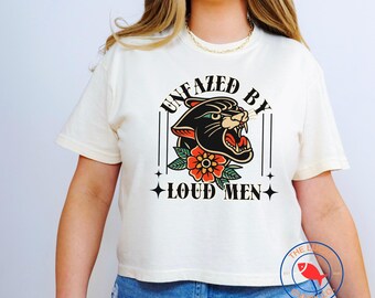 May include: A white cropped t-shirt with a black panther graphic and the text "Unfazed by Loud Men".