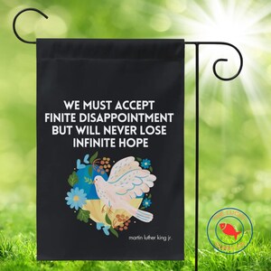 May include: Black garden flag with the quote "WE MUST ACCEPT FINITE DISAPPOINTMENT BUT WILL NEVER LOSE INFINITE HOPE" and a dove illustration. The flag also features the text "martin luther king jr."