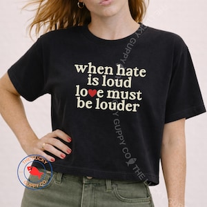 May include: Black cropped t-shirt with the text "when hate is loud love must be louder" in white. The shirt has a crew neck and short sleeves. The Lucky Guppy Co. logo is visible.
