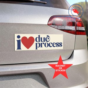 May include: A white car with a red heart and blue text that says "I ♥ due process" on a bumper sticker. The sticker is a magnet or sticker.