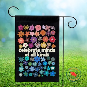 May include: Black garden flag featuring a colorful floral design with the words "celebrate minds of all kinds" in white. The flowers are in various colors, including pink, orange, blue, and yellow. The flag is hanging on a black metal stand.