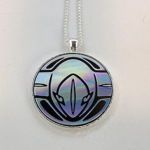 May include: A silver chain necklace with a round pendant featuring a black and white graphic design on a iridescent background.
