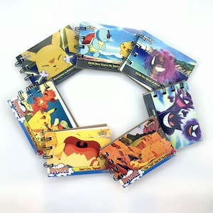 May include: A set of eight small spiral bound notebooks featuring Pokemon characters and episode titles from the anime series. The covers are colorful and feature various Pokemon, including Pikachu, Squirtle, and Ghost.
