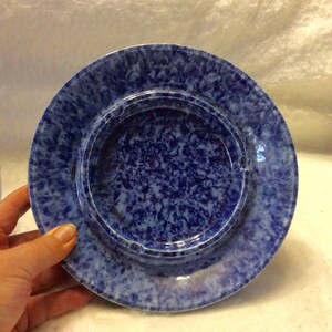 May include: Blue and white ceramic ashtray with a mottled glaze. The ashtray has a raised rim and a deep well.