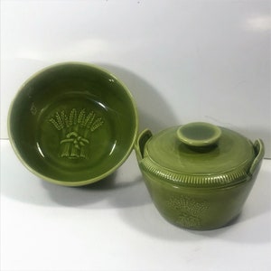 May include: A set of two green ceramic bowls with a wheat design. The larger bowl has a lid.
