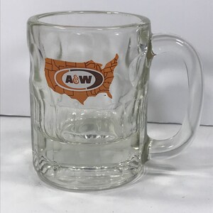 May include: A clear glass mug with a handle. The mug has a raised design and features a logo of A&W Root Beer with a map of the United States.