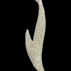 May include: A silver-colored, beaded, abstract floral design. The design is made of small, rectangular beads that are arranged in a flowing, organic pattern.