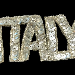 May include: A silver sequined patch that spells out the word "ITALY".