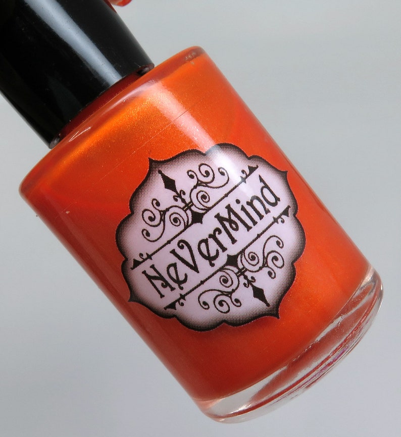 May include: A small orange bottle of nail polish with a black cap. The bottle has a label with the words "NeverMind" in a decorative font.