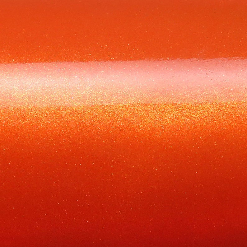 May include: A close-up of a bright orange surface with a subtle shimmer. The surface has a slightly textured appearance, giving it a metallic look.
