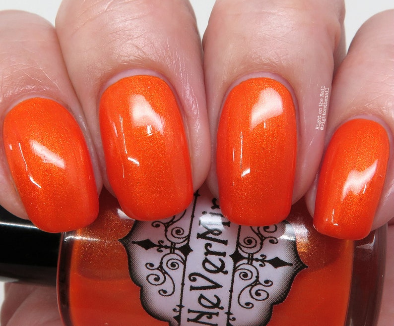 May include: Orange nail polish with a glossy finish. The bottle is labeled "The Verni", with a black and white design.