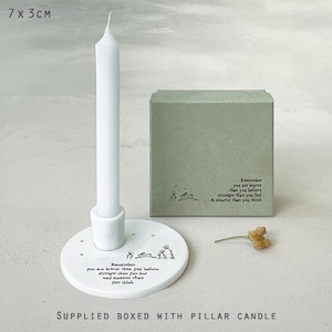 May include: White ceramic candle holder with a white pillar candle. The holder has a round base with a quote that reads "Remember you are braver than you believe, stronger than you feel, and smarter than you think." The candle holder is packaged in a green box with the same quote.