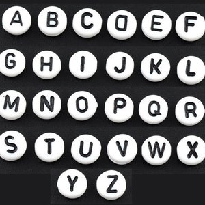 May include: White round alphabet letter beads with black lettering. The beads are arranged in alphabetical order from A to Z.